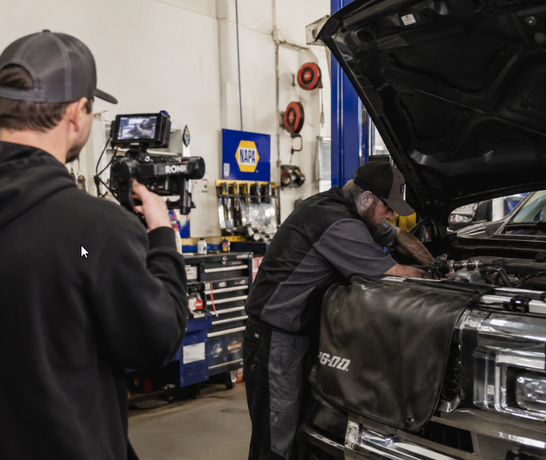 Camera operator filming service work at an auto repair shop