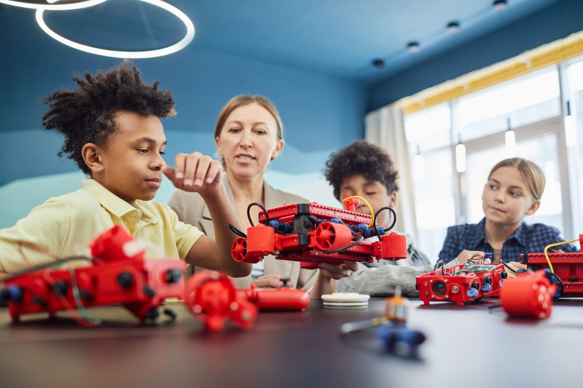 A teacher helping students build robots