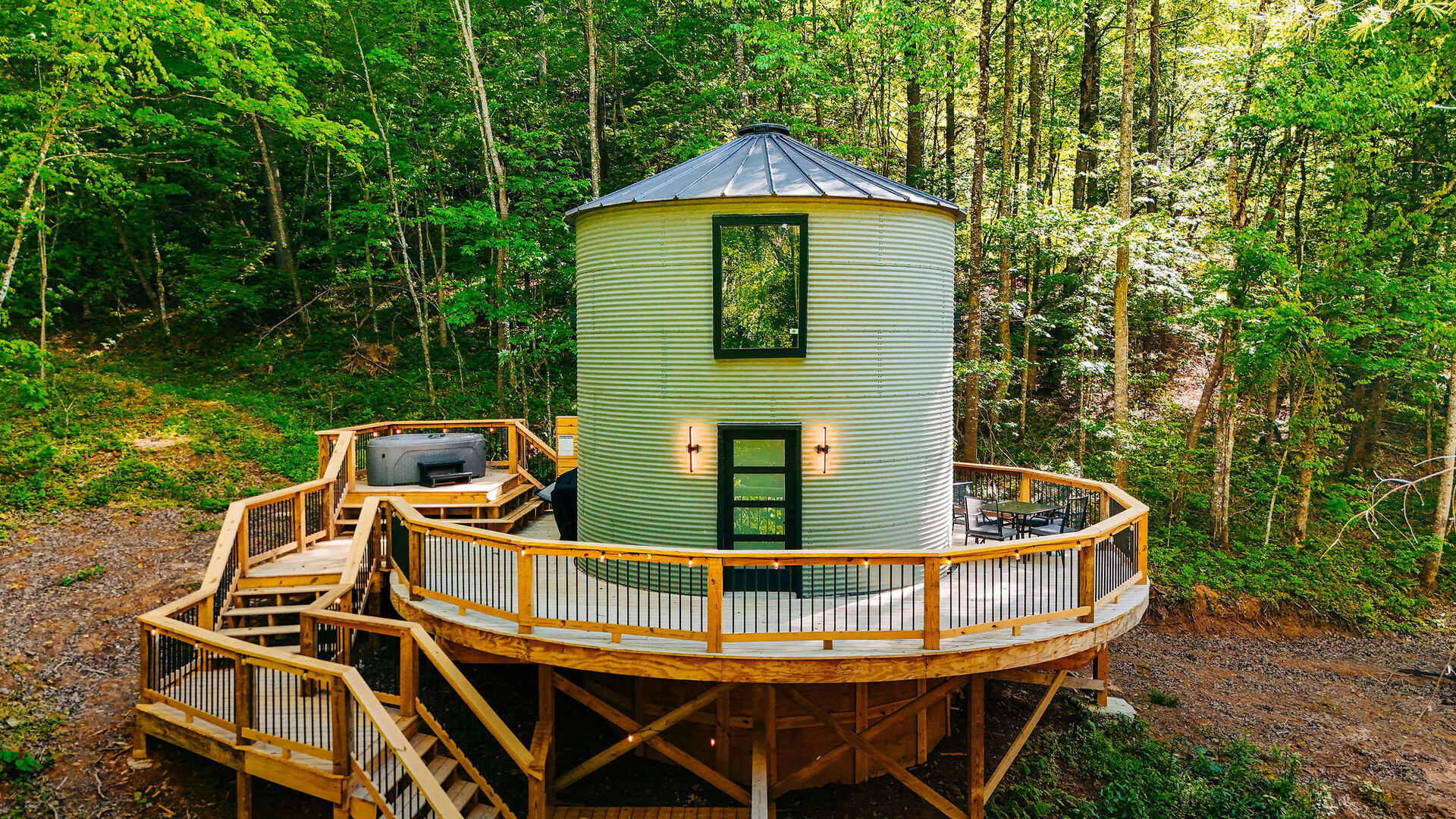 Aerial view of The Yoder silo cabin and its wrap-around deck in the forest