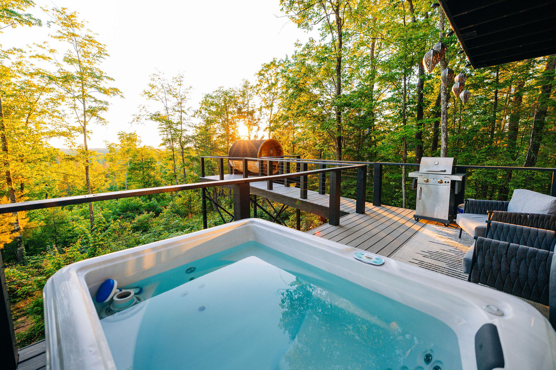Private hot tub on the deck of The Onyx at golden hour, surrounded by forest