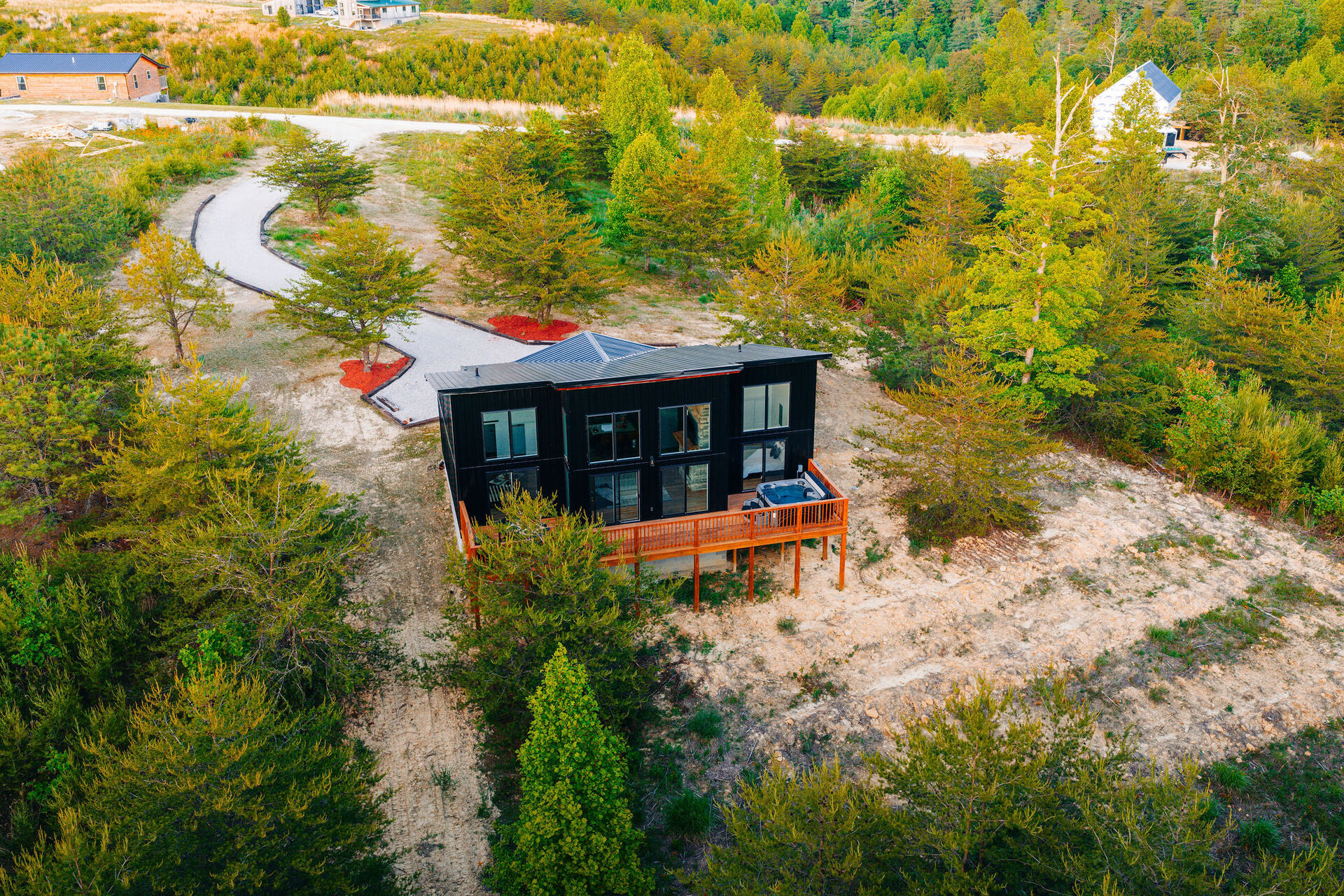 The Blackstone, a modern black cabin overlooking a blue quarry pond from the cliff edge