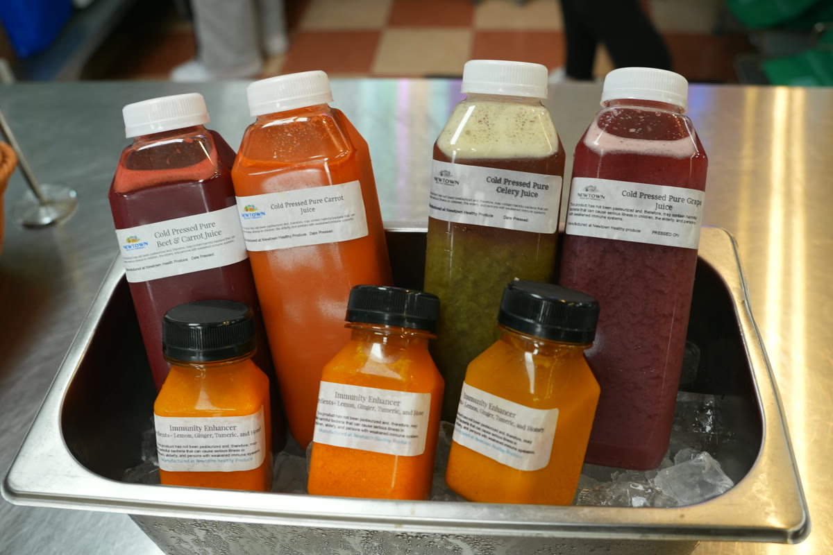 Bottles of fresh carrot, beet, grape, and celery juice lined up on the counter