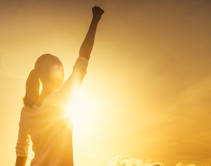 Woman raising fist in sunset because she has made changes to better her life