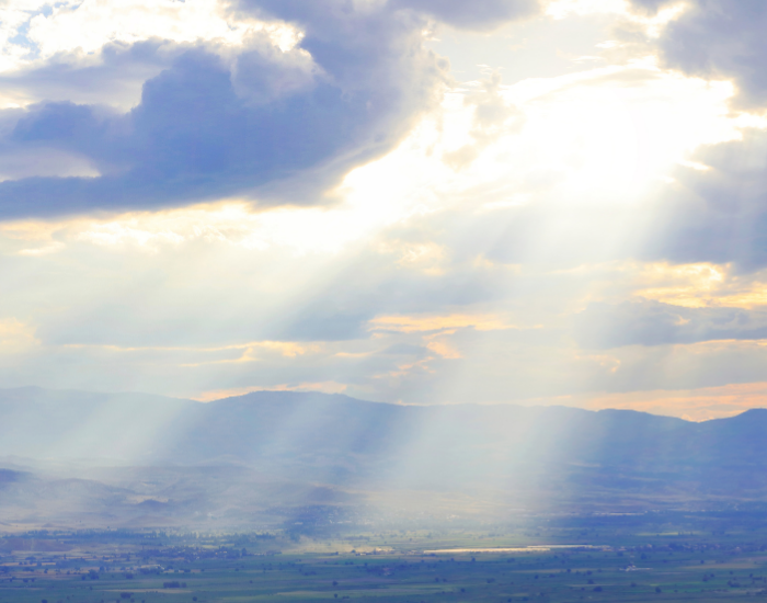 Beautiful sunlight through clouds over ocean with mountains in behind. Represents rewriting the hidden codes that controlling your life.