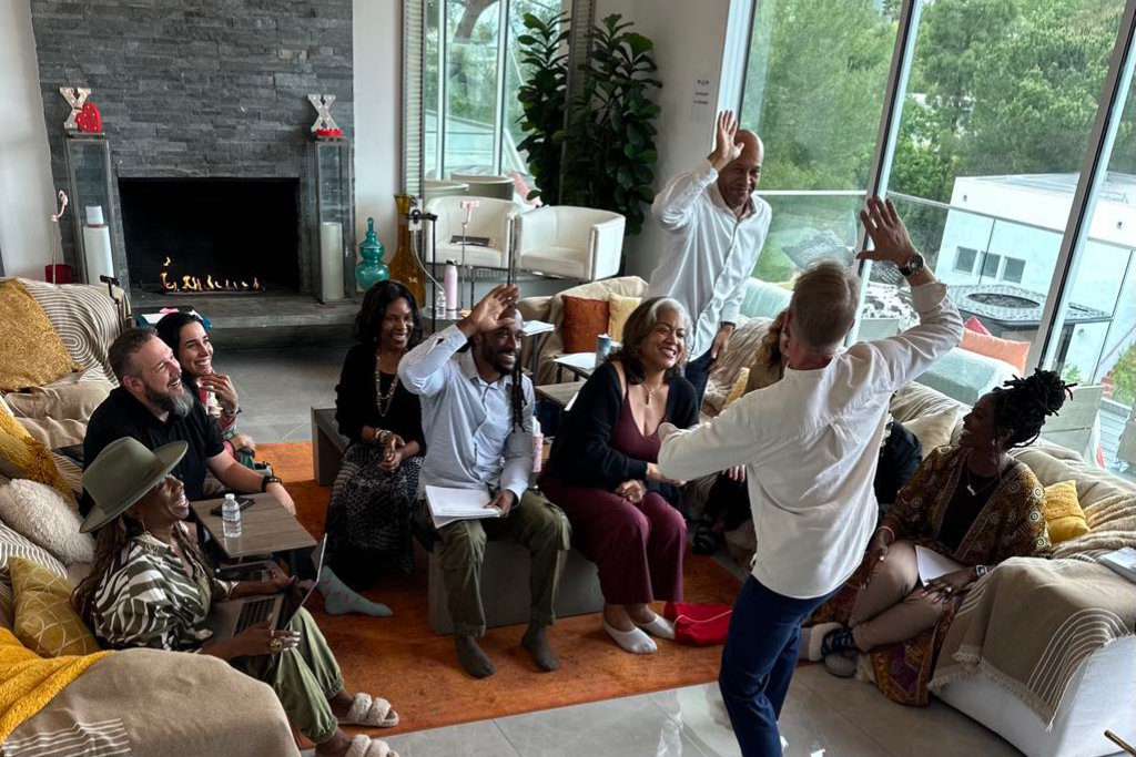 Dr. Stacey Kevin Frick high fiving an excited audience member during an in-person event hosted by Lisa Nichols.