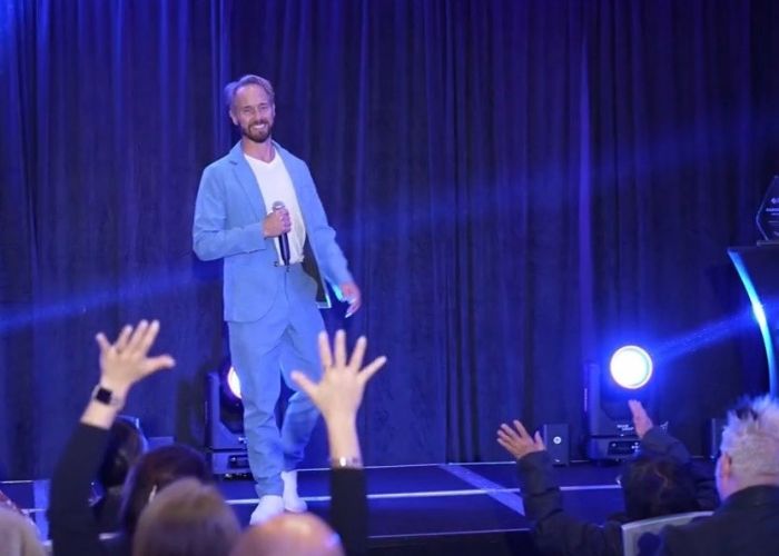 Stacey Frick speaking on stage at an event with an enthusiastic audience