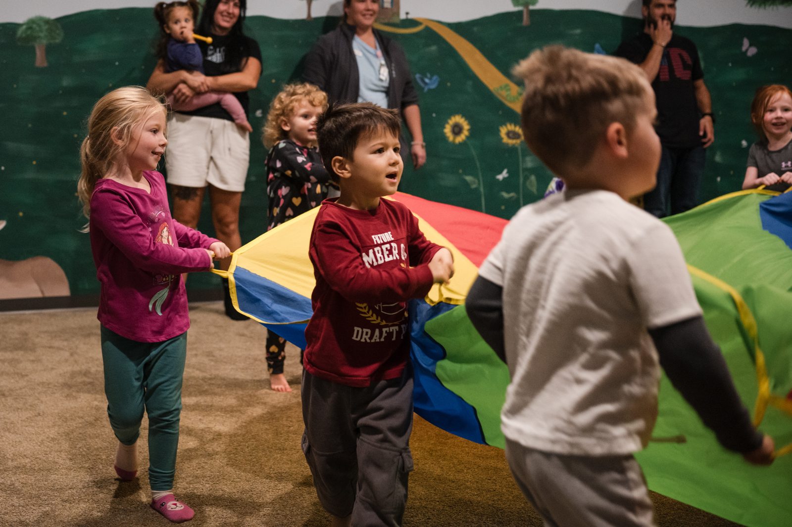 Musikgarten children playing with a rainbow parachute