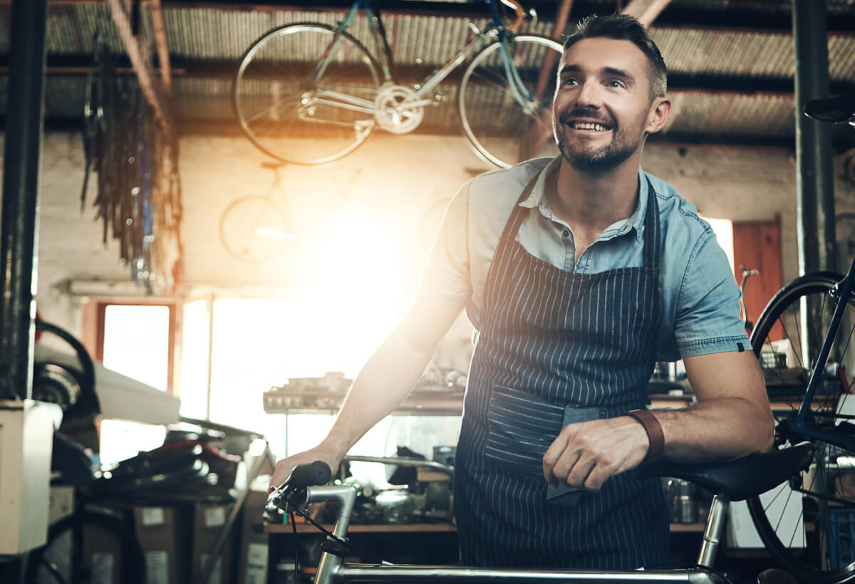 Bicycle repair shop owner in his workshop, smiling, hands on a bike