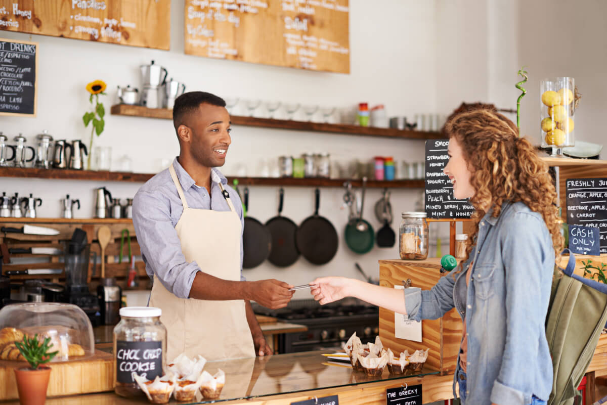 A customer paying at a cafe counter — a sale that closes itself