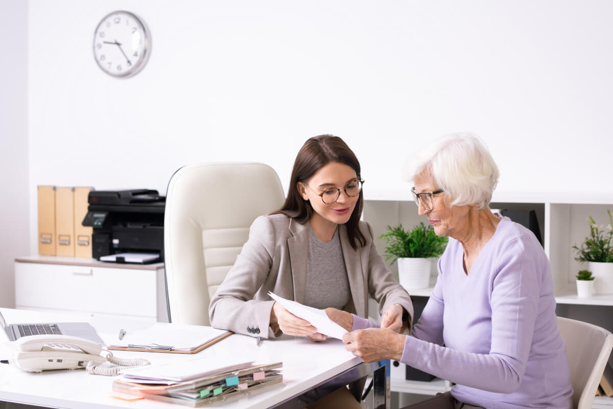 Advisor walking an older client through paperwork across a desk