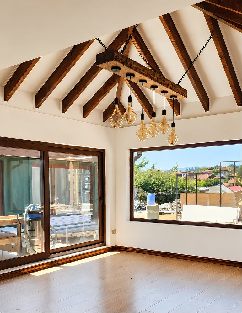Living con techo a tres aguas, vigas de madera a la vista y ventanales hacia el exterior