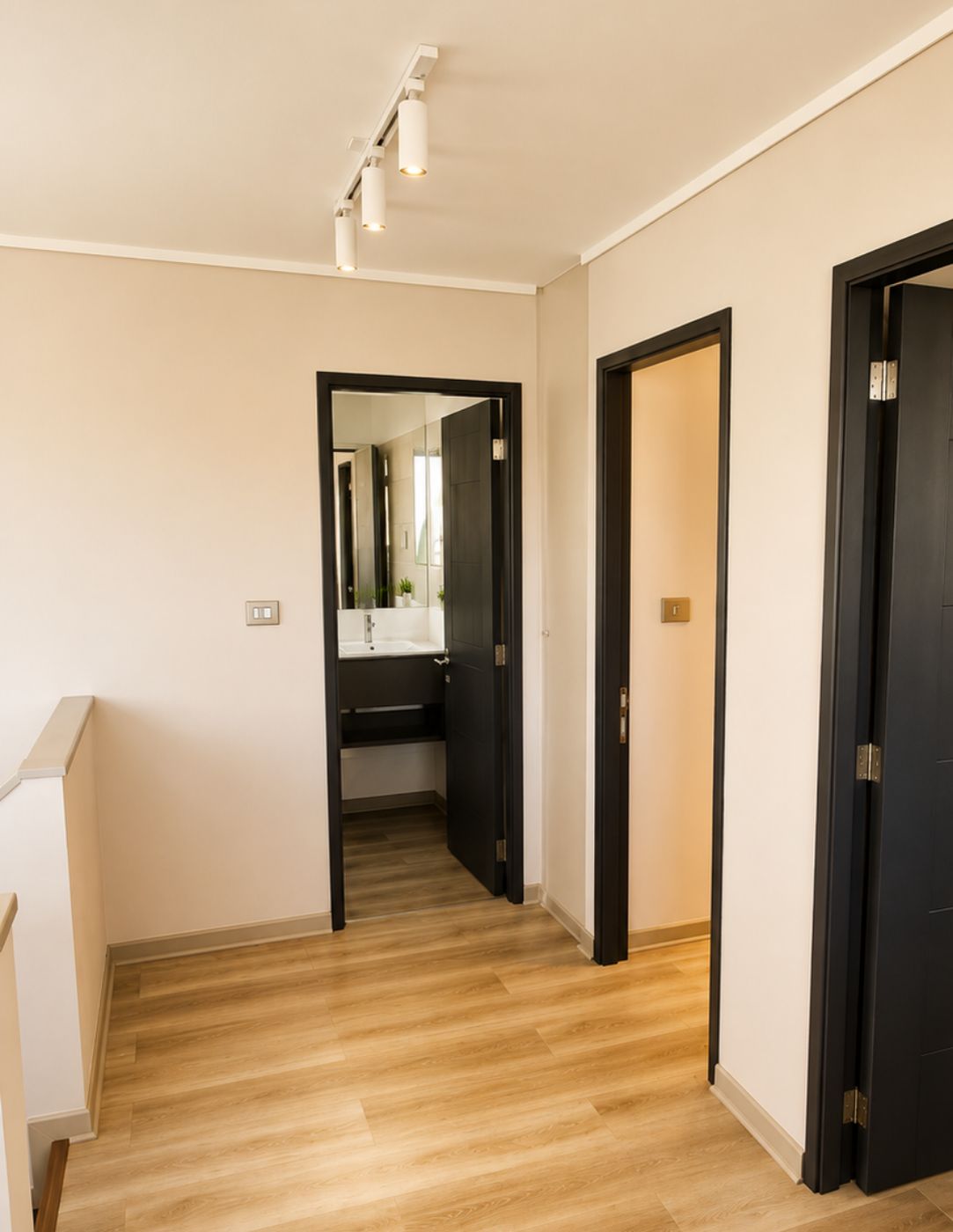 Pasillo del segundo nivel remodelado, con piso flotante, puertas negras y rieles de luz