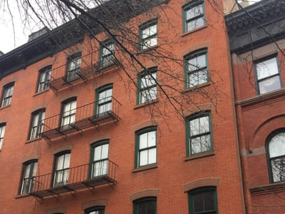 Renovated brick apartment building with green-trimmed windows in Queens