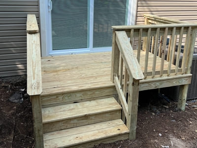 Custom-built wooden ramp and steps leading to a patio door in a Queens home, showcasing sturdy craftsmanship.