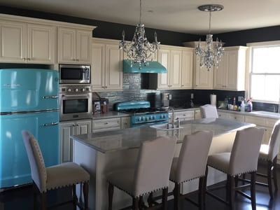 Manhattan kitchen renovation with white cabinets, vintage blue appliances, and chandeliers.