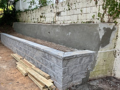 Concrete garden retaining wall under construction in Staten Island, featuring a newly installed stone border.