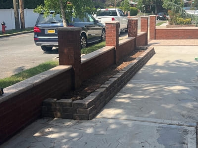 Inside view of a brick fence installation in Staten Island, highlighting the clean and organized layout of the driveway and garden area.