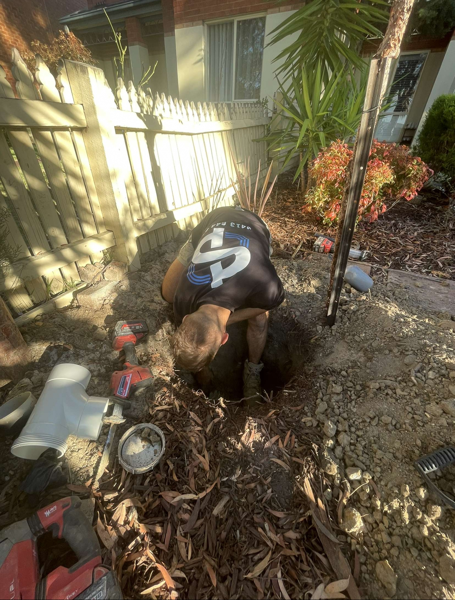 SPD Plumbing technician digging a trench for pipe work