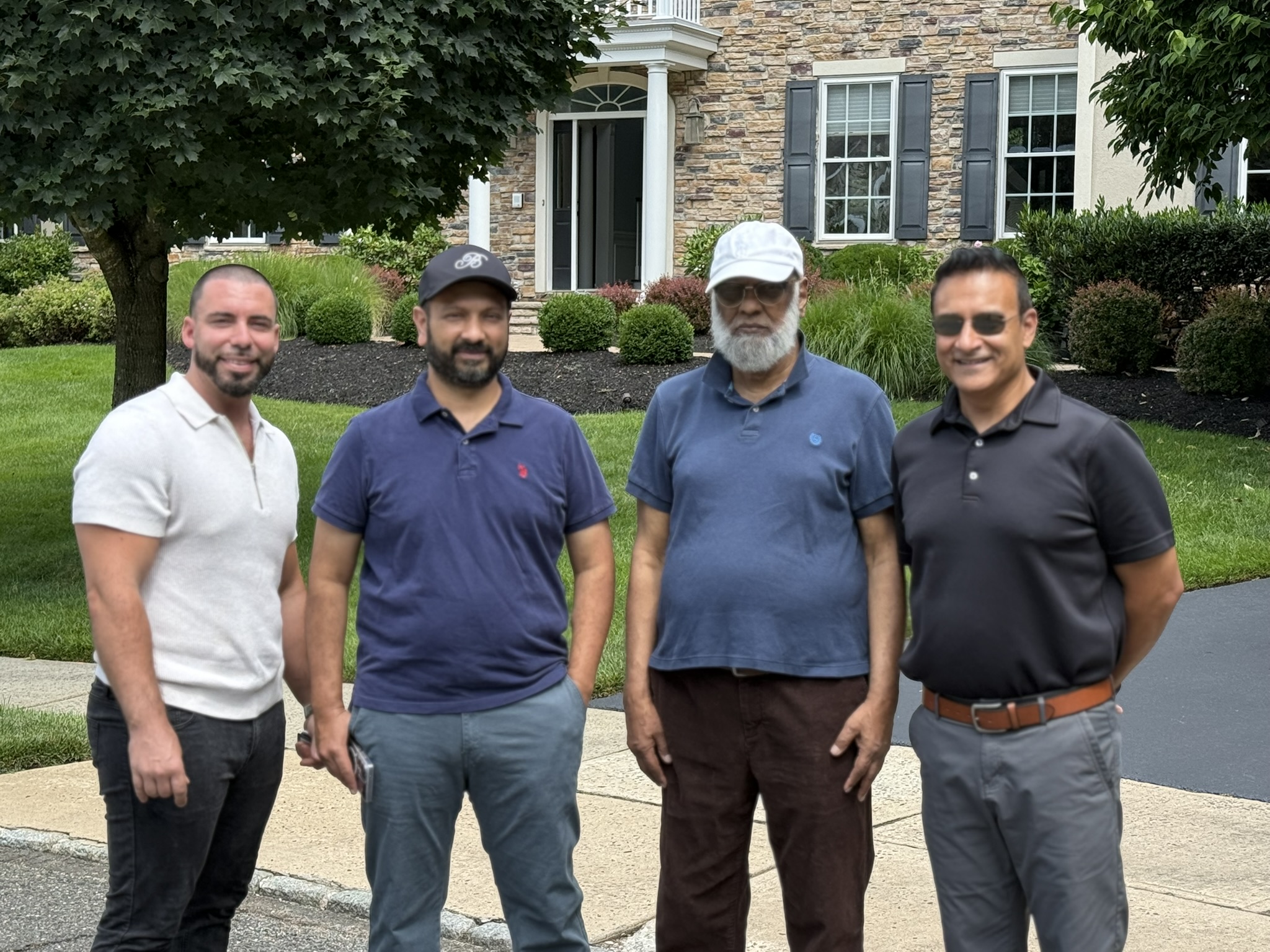 Four people gathered outside a stone-front home.