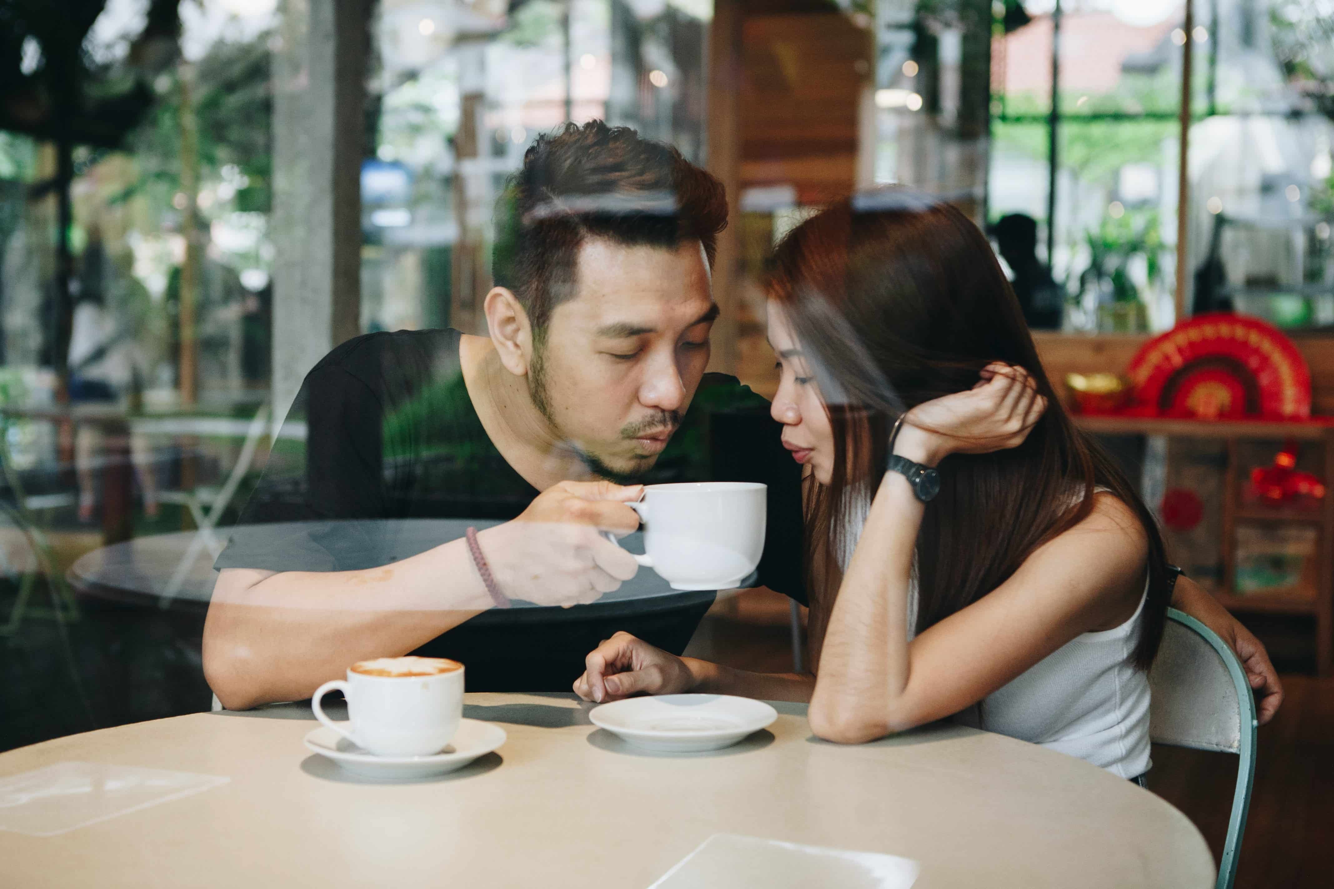 Couple sharing a coffee, seen through the window.