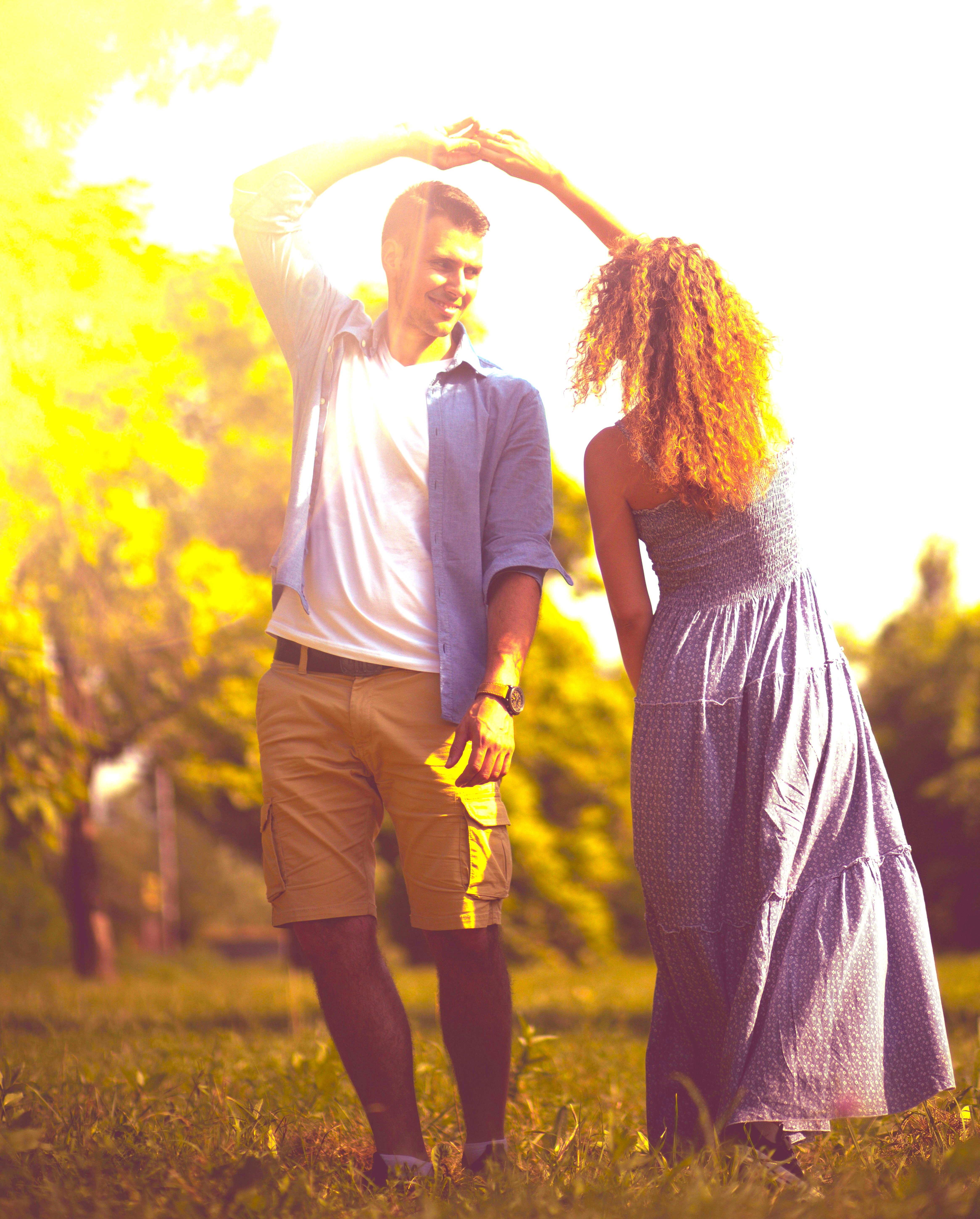 Couple twirling in a field with trees