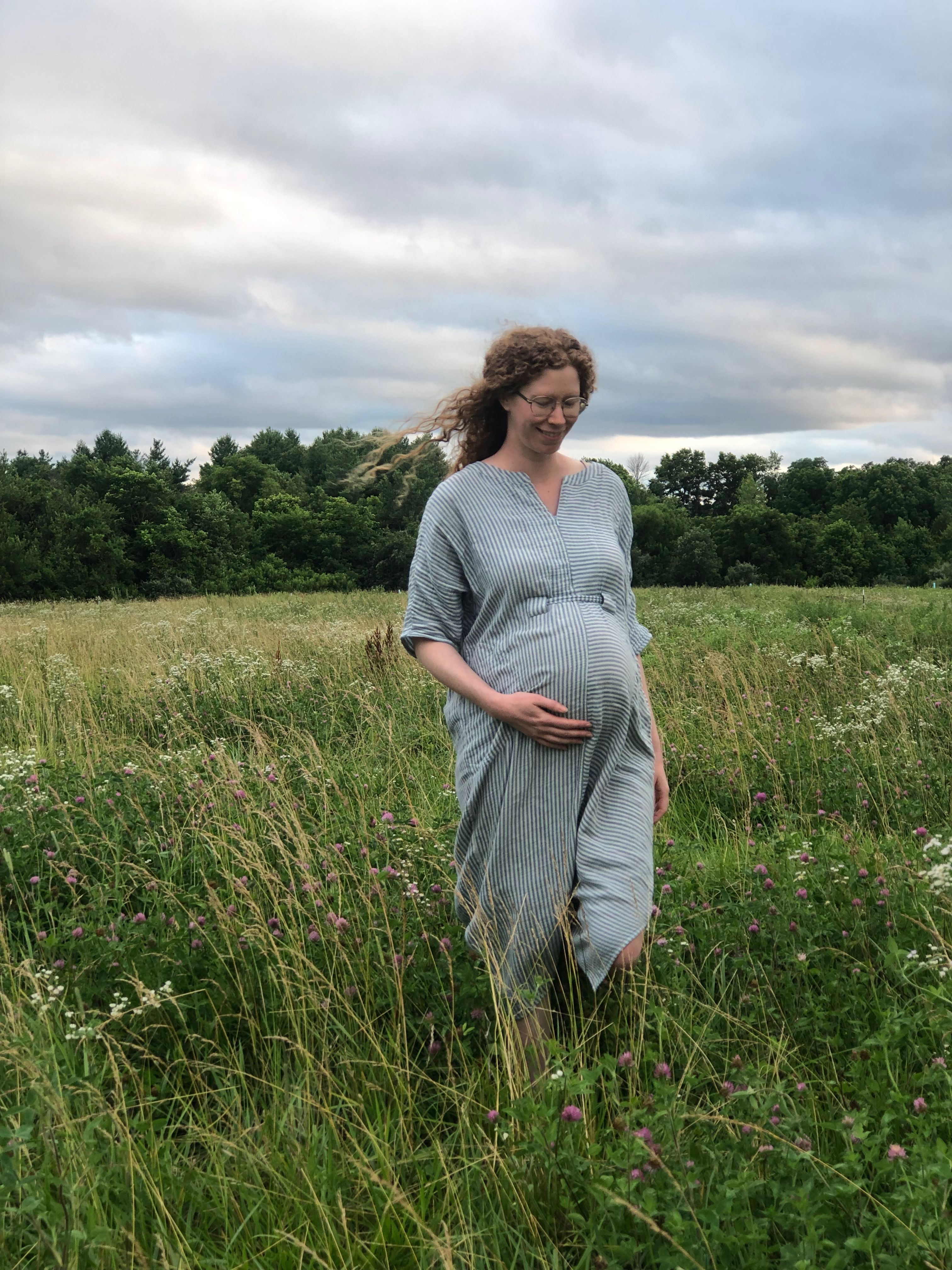 a pregnant woman walks through a pasture