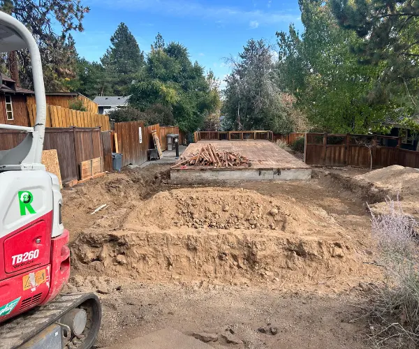 Site prepping with an excavator in Bend for a garage addition foundation