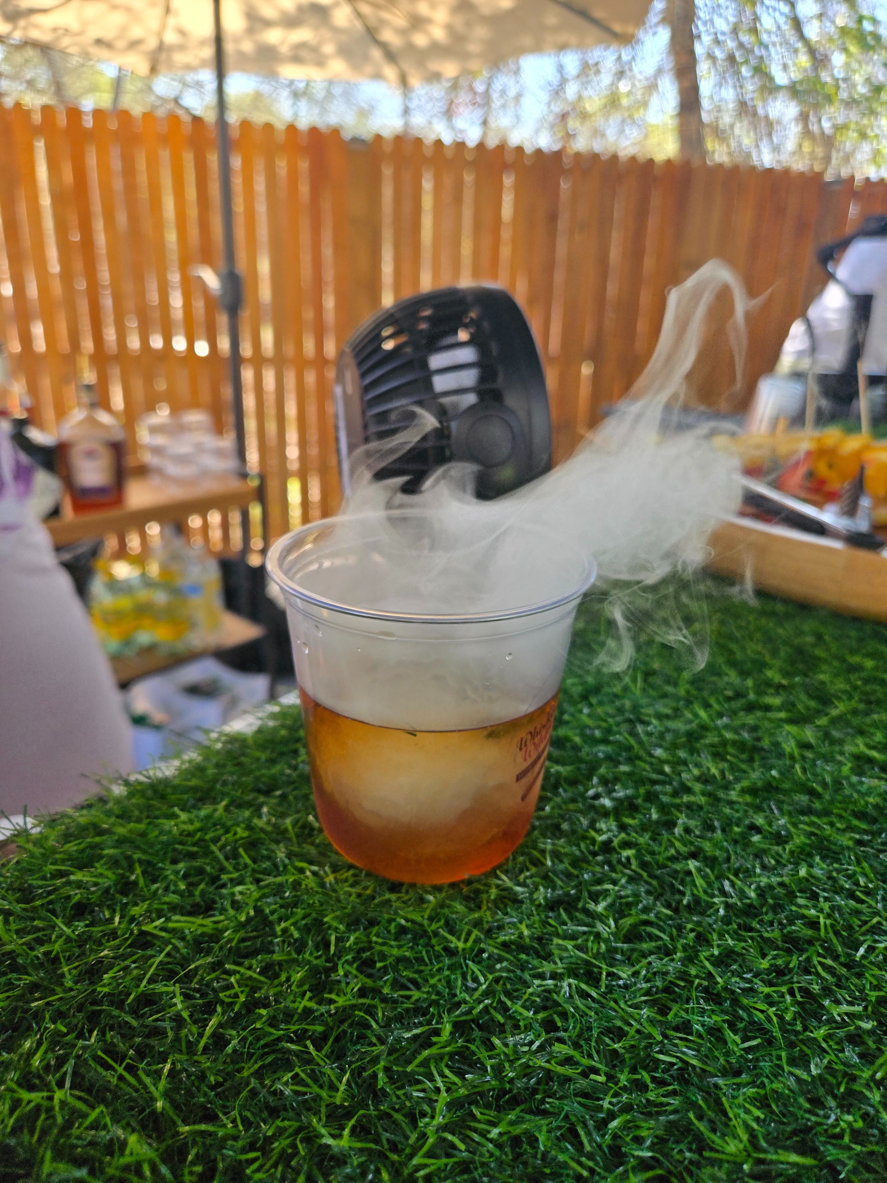 Smoked cocktail with visible smoke rising from the glass at an outdoor bartending event