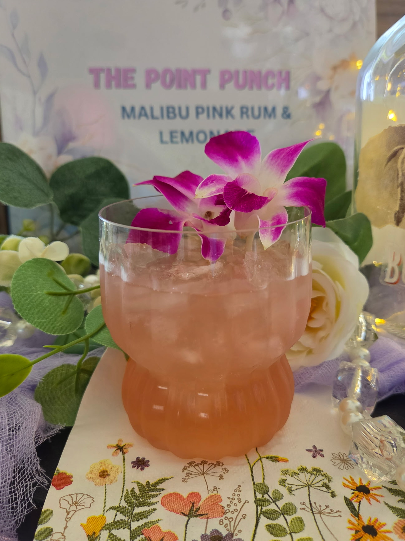 The Point Punch cocktail with orchid garnish and printed recipe sign reading Malibu Pink Rum and Lemonade