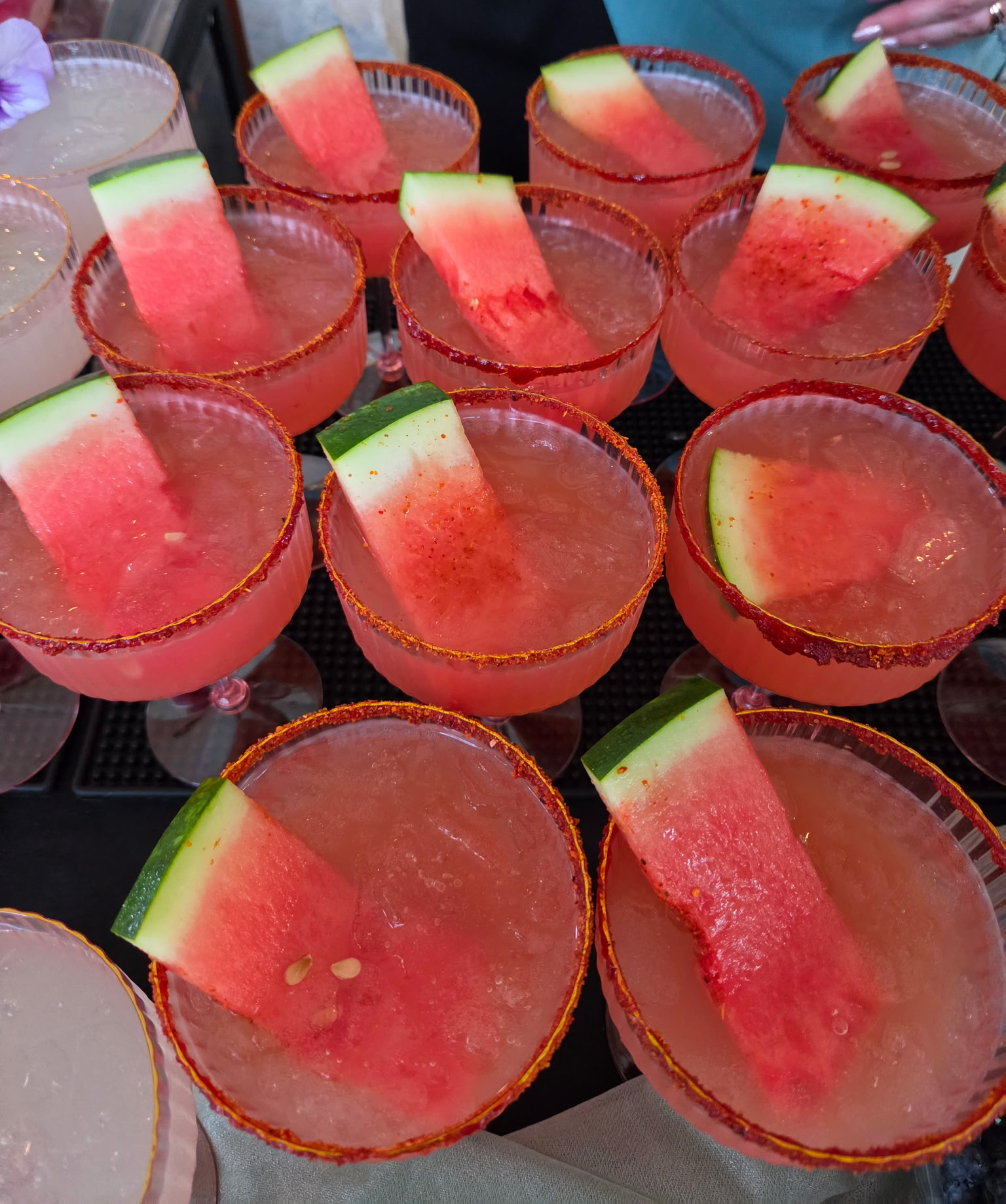 Rows of watermelon margaritas with chili-salt rims and watermelon wedge garnish