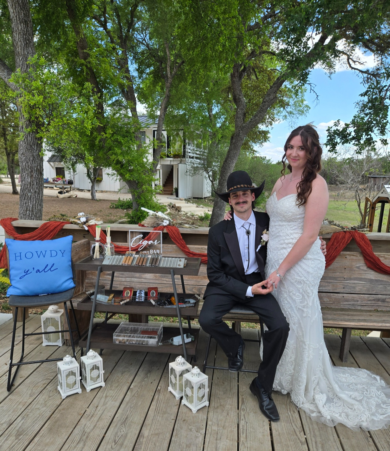Bride and groom pose beside the branded cigar bar cart on their wedding day