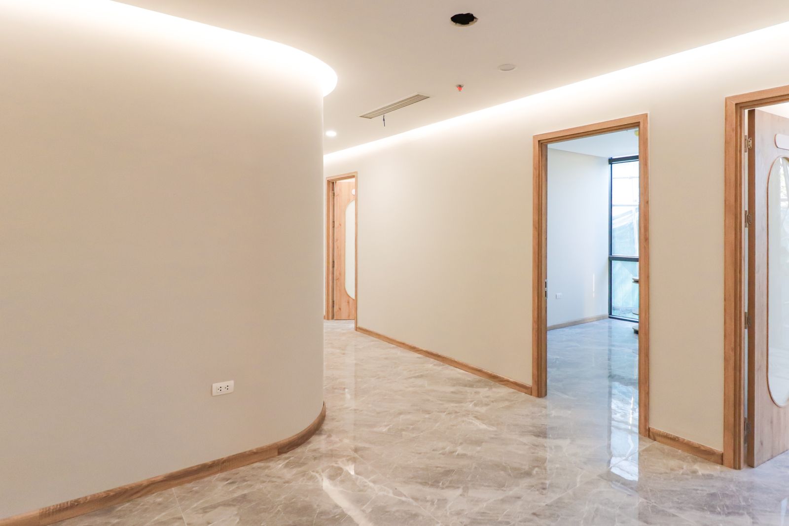 Bright minimalist corridor with marble flooring and wooden door frames
