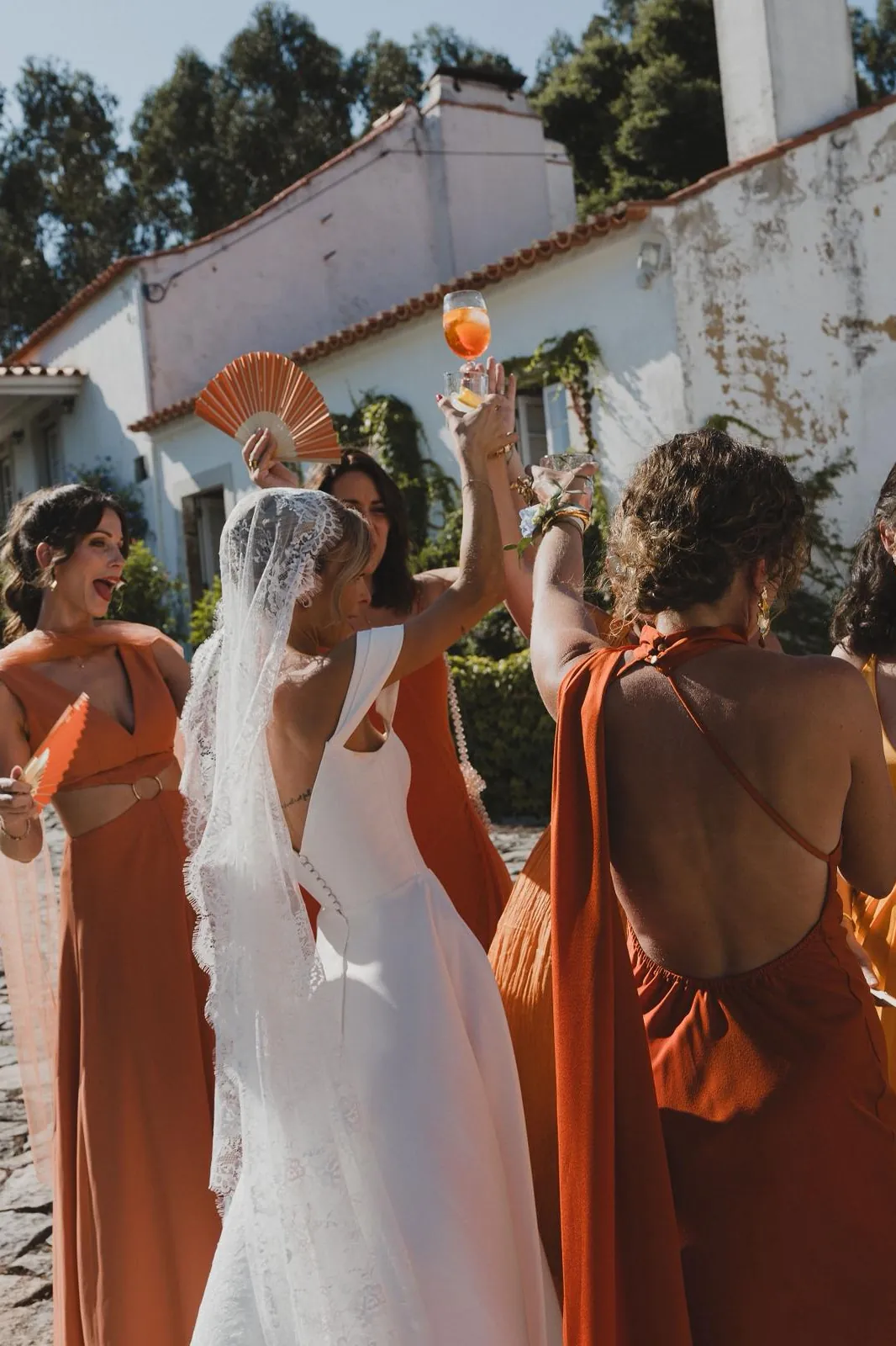 Braut und Brautjungfern in Terrakotta stossen bei einer Hochzeit in Portugal an