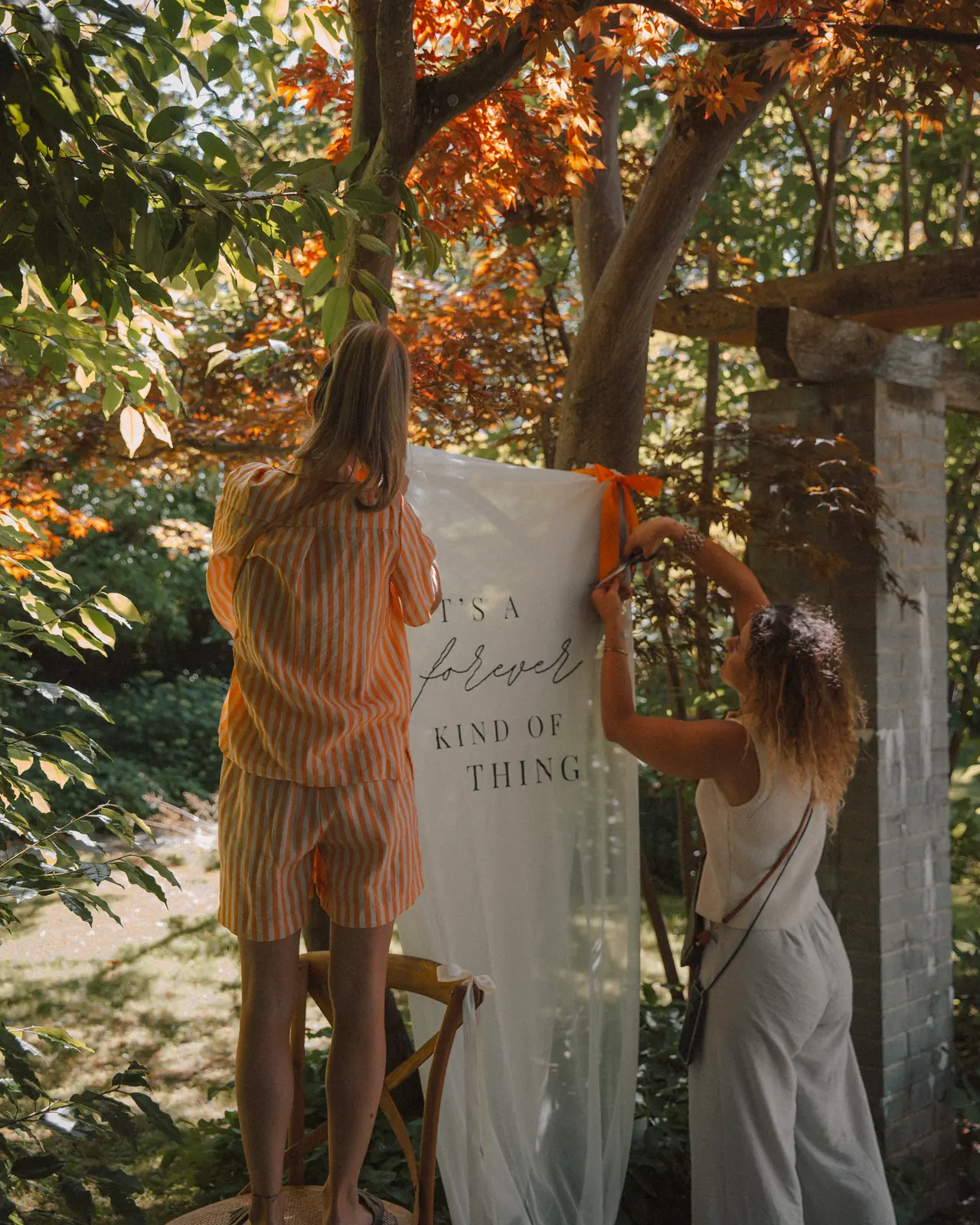Andrea und Kim von Cin Cin hängen im Botanischen Garten St. Gallen ein Willkommensbanner auf