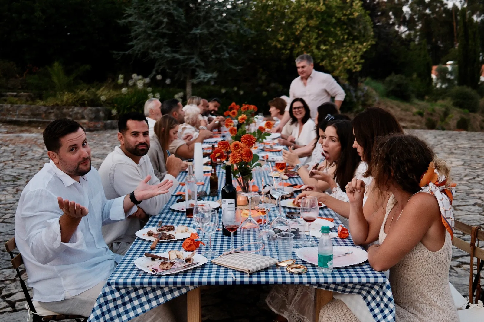 Gäste lachen beim Pre-Dinner an einem Tisch mit blau-weissem Tischtuch in Portugal
