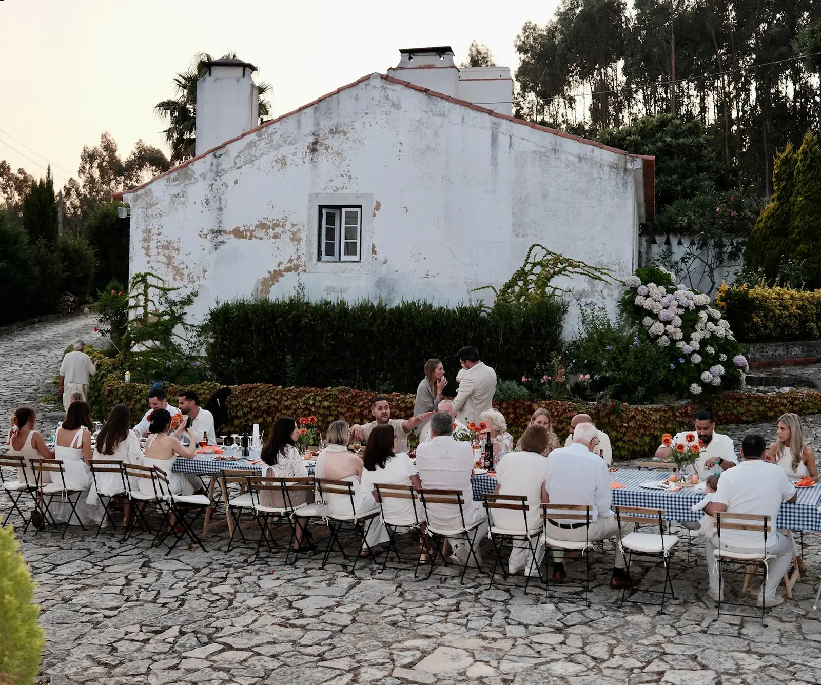 Lange Tafel mit Gästen vor einem weissen Landhaus in Portugal