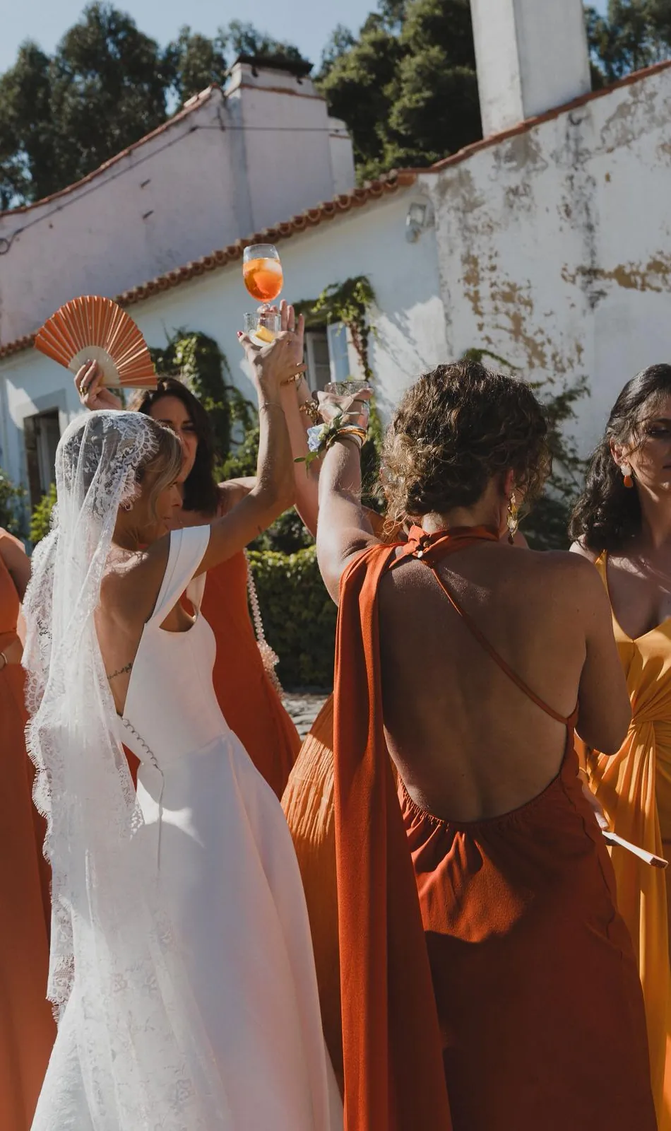 Braut und Brautjungfern in Terrakotta stossen bei einer Hochzeit in Portugal an