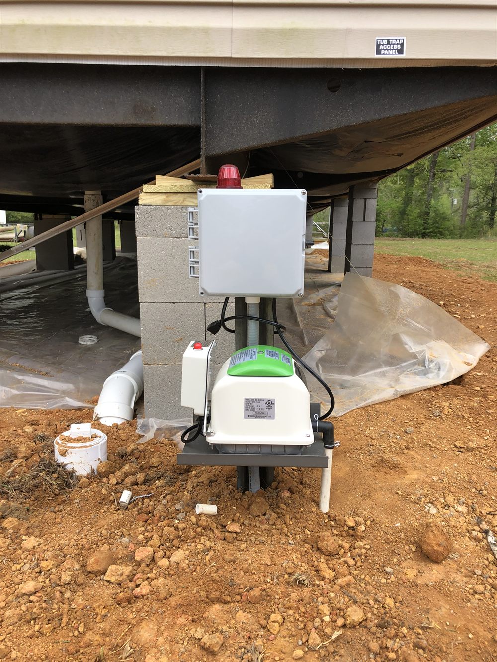 A treatment-plant control panel and pump installed by Holmes Septic under a home