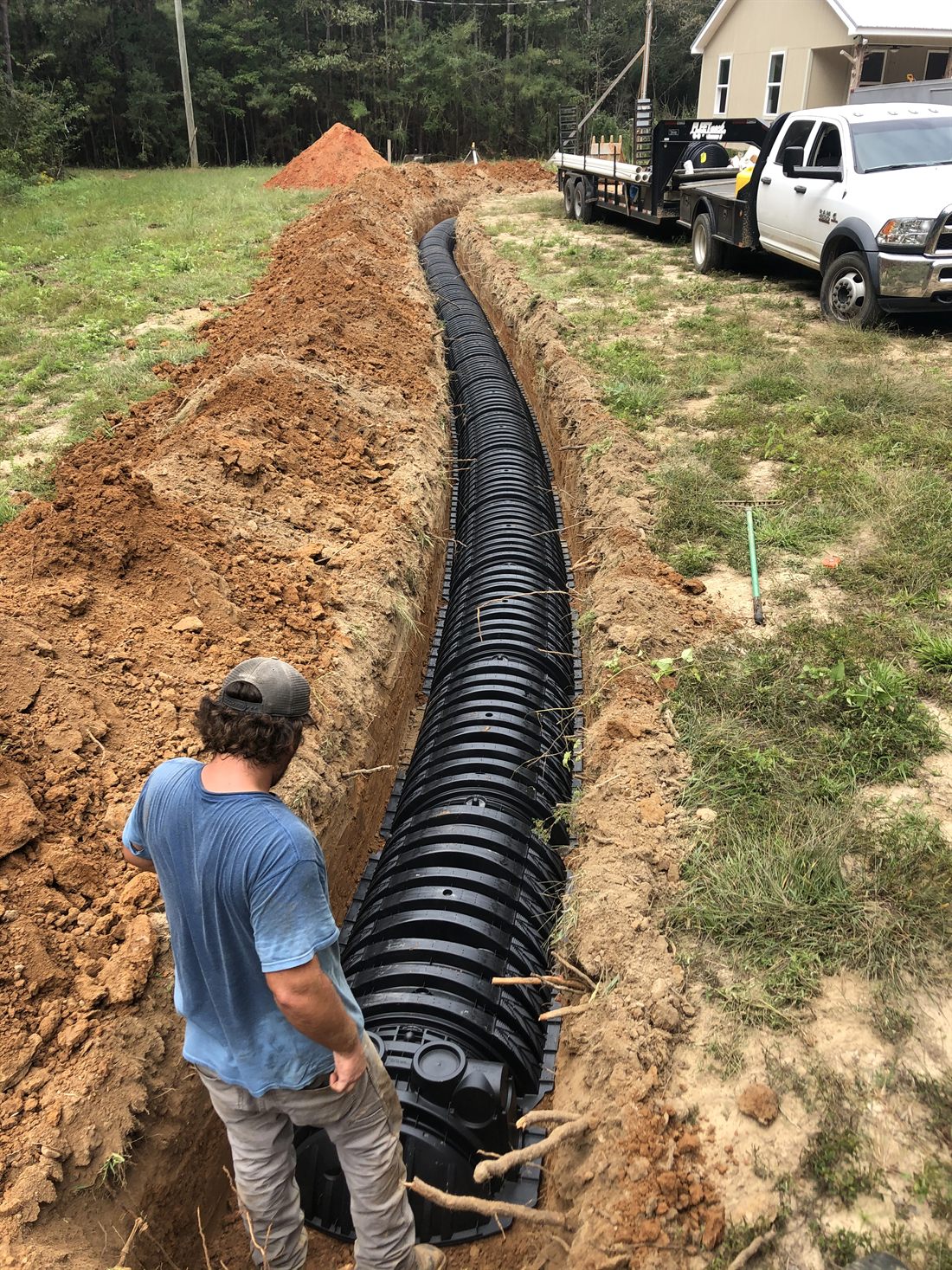 Holmes Septic crew installing an Infiltrator chamber drain-field line in a trench