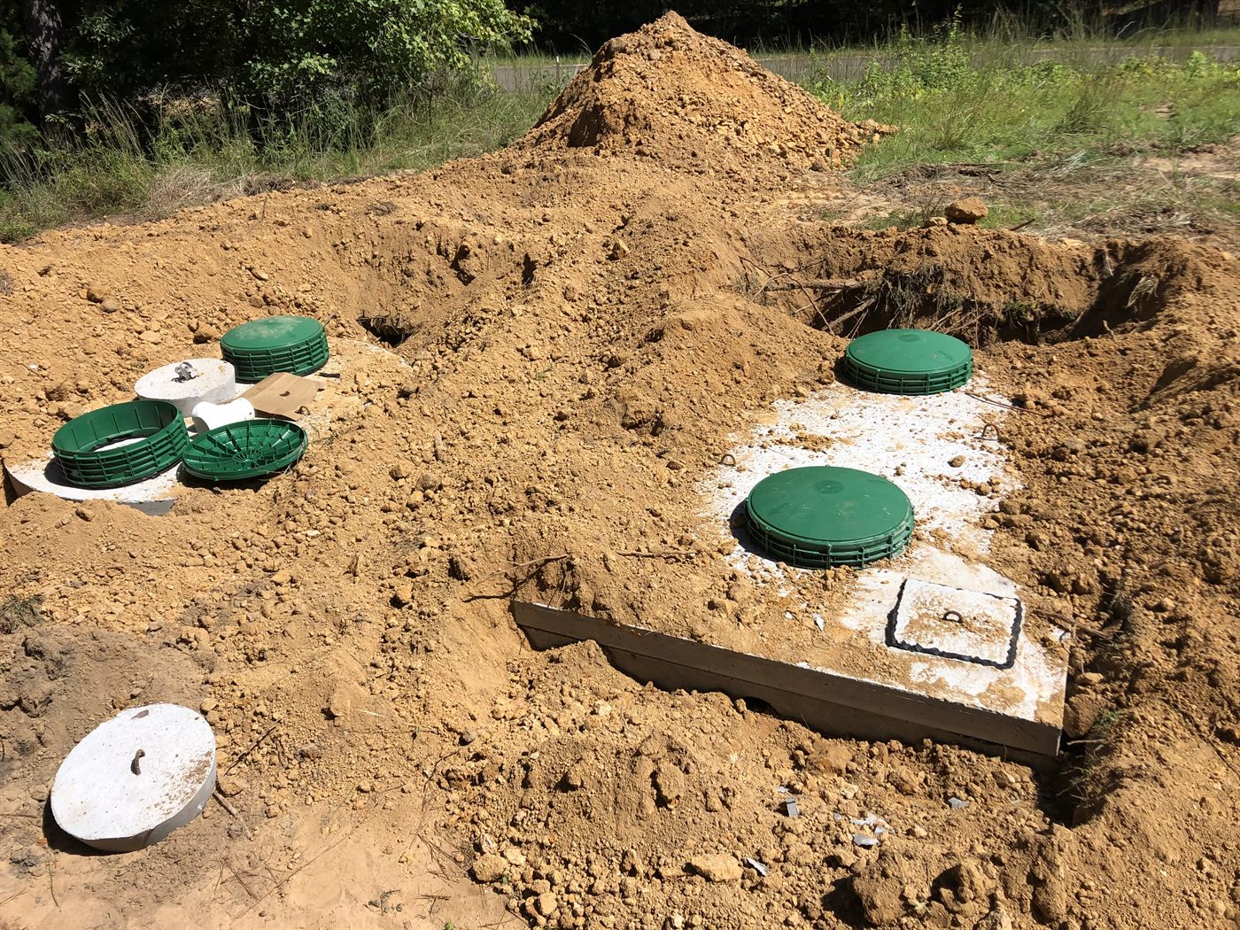 A completed Holmes Septic installation — tank and treatment-plant access risers set flush in the yard