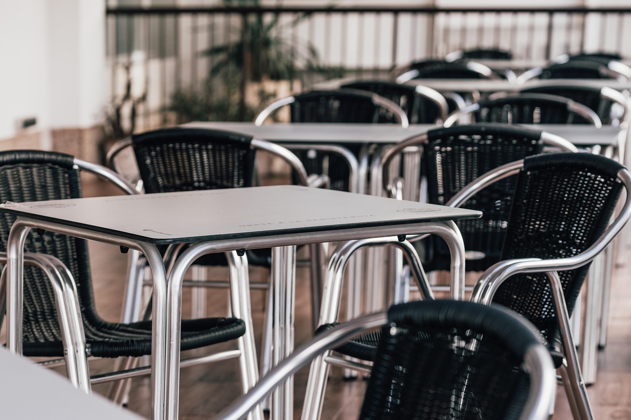 restaurant with wicker chairs and wood tables, all tables are empty
