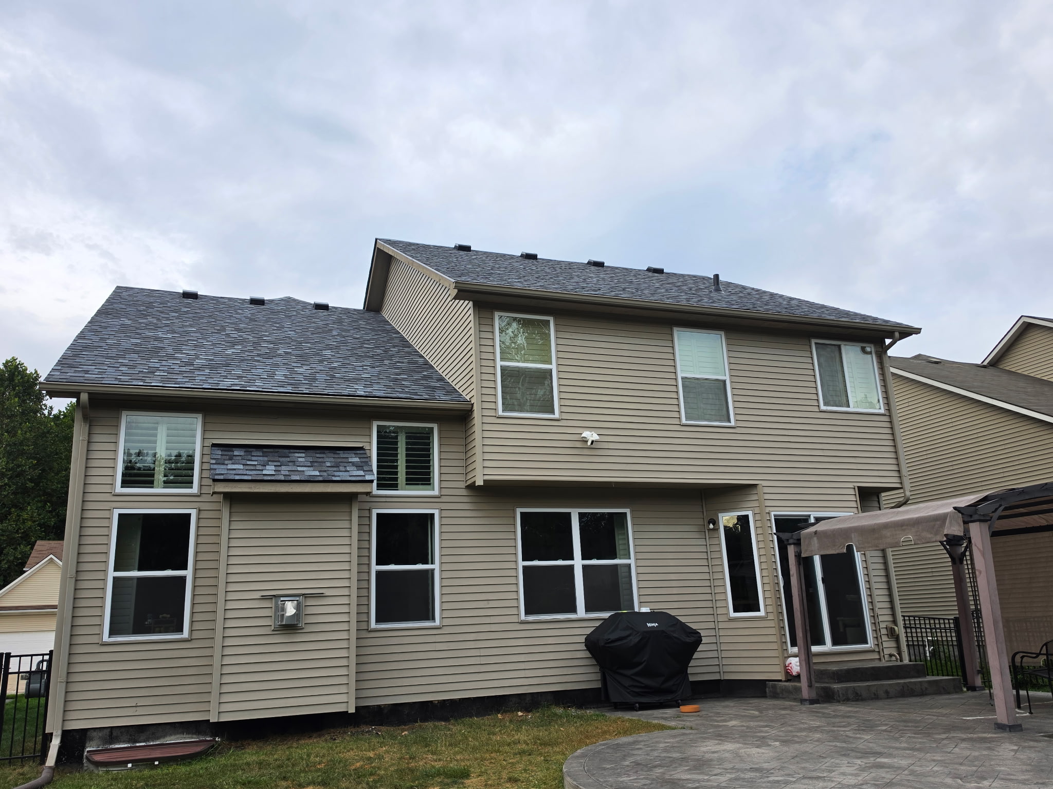 Rear elevation of a two-story home with new shingles across multiple roof planes and dormers.