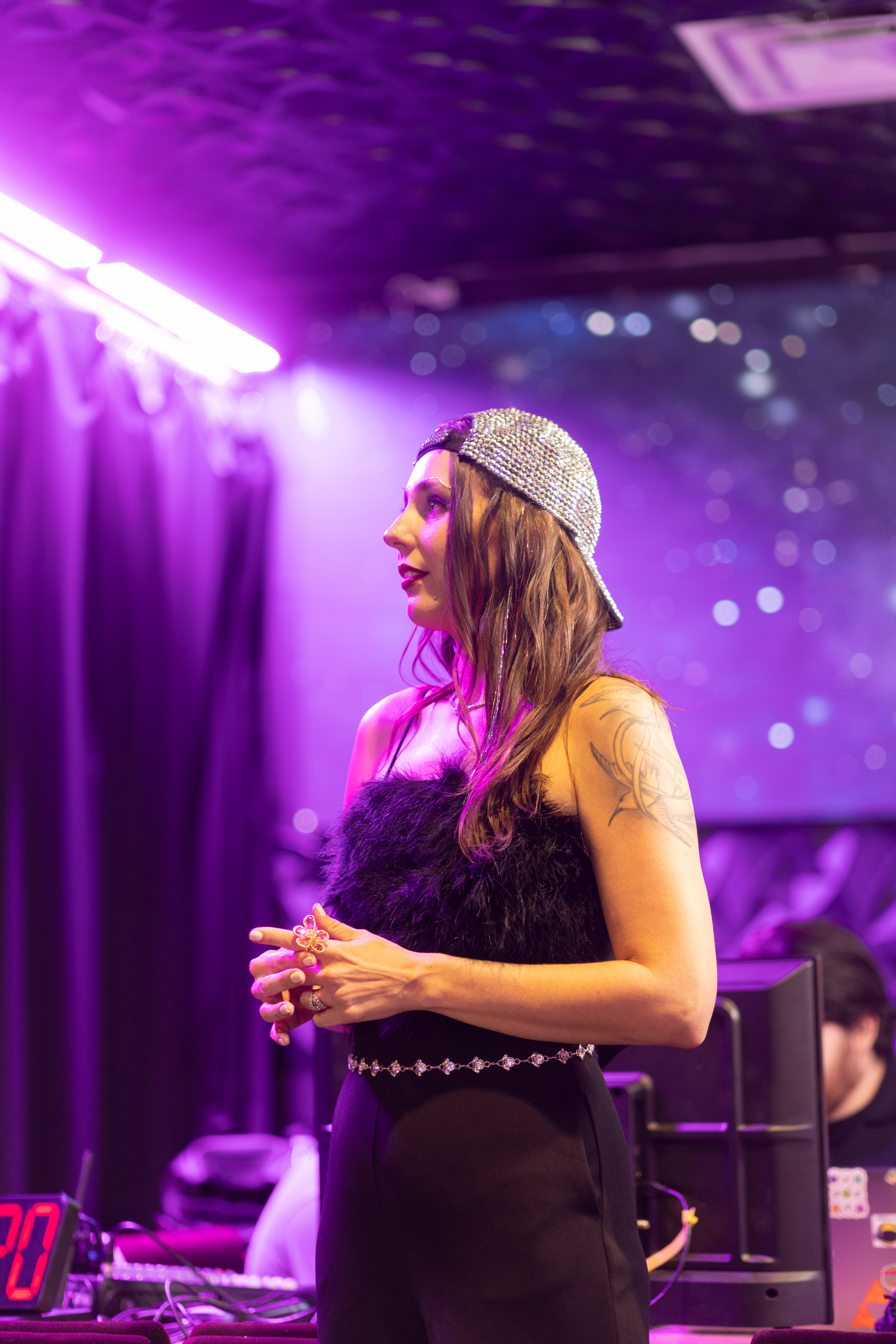 A speaker holding a microphone under purple stage lighting.