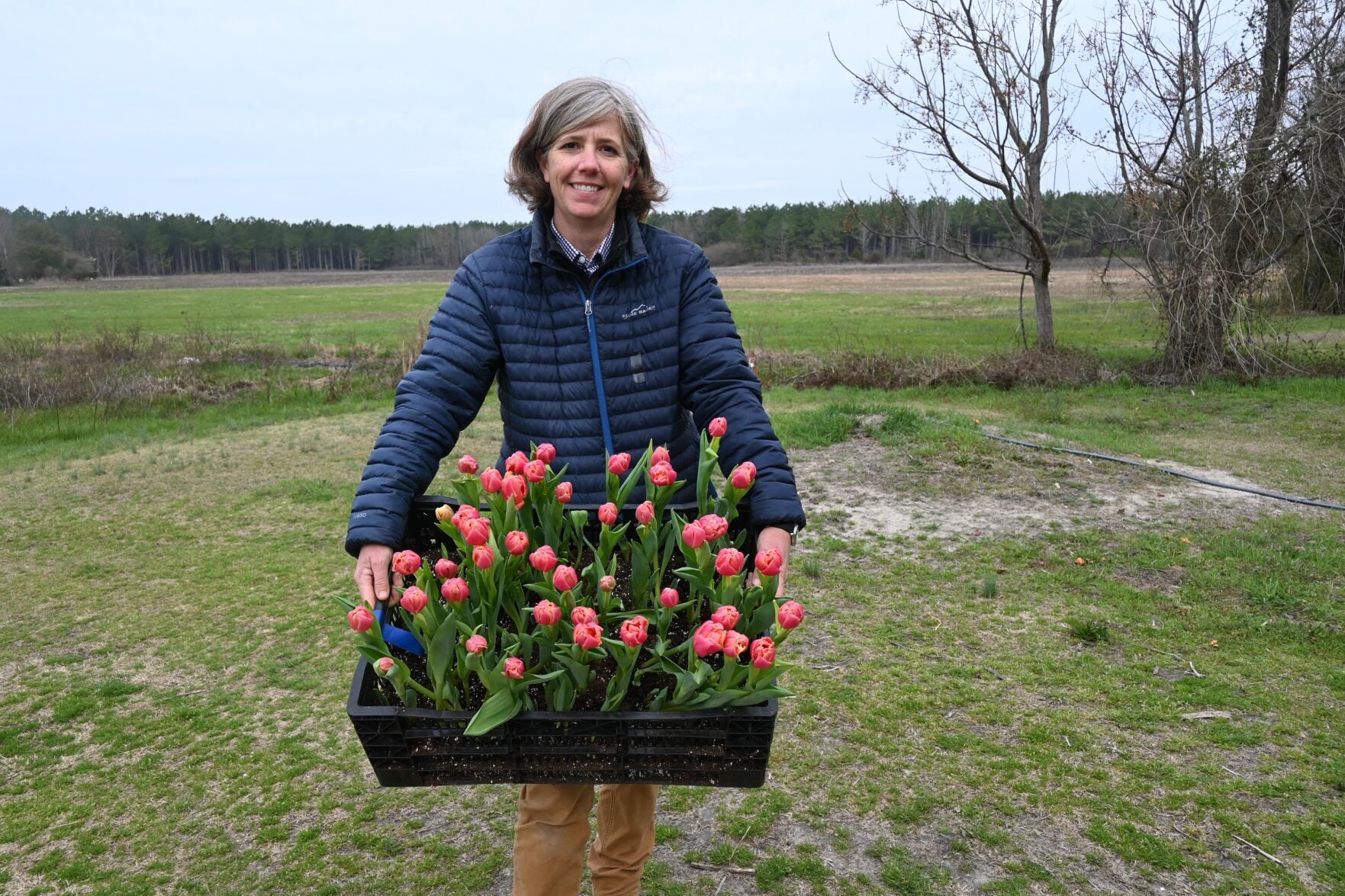 Erica Goza of Branching Out holds a crate of tulips at her farm in Mayesville.