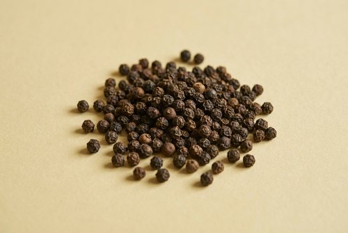 Džiovintas ingredientas ant kreminio fono: Juodieji pipirai.