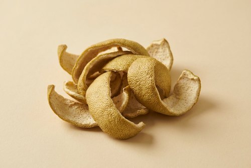 Džiovintas ingredientas ant kreminio fono: Džiovinta pomelo žievelė.