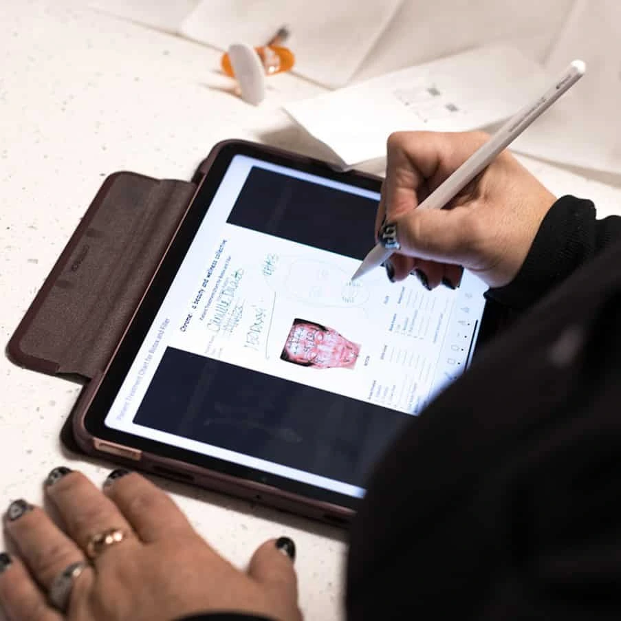 Medical training showing facial anatomy and key injection points on a tablet