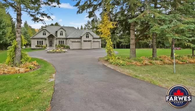 Grey stone Farwes custom home with a three-car garage and circular driveway