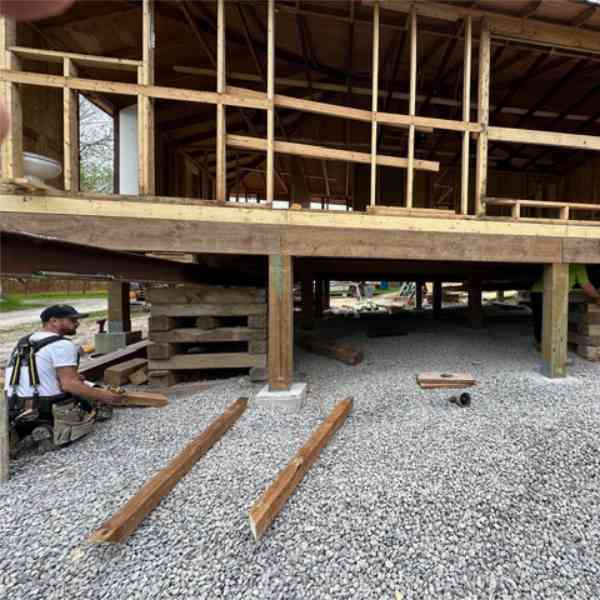 Farwes addition framing with a raised floor, posts, and a carpenter on site