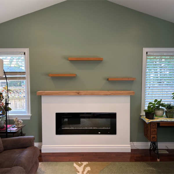 Farwes fireplace with a white surround, oak mantel, and floating wood shelves